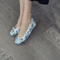 Alt text: Elegant ballerina flats in an azure hue with a classic print, showcasing a rounded toe and a bow detail.